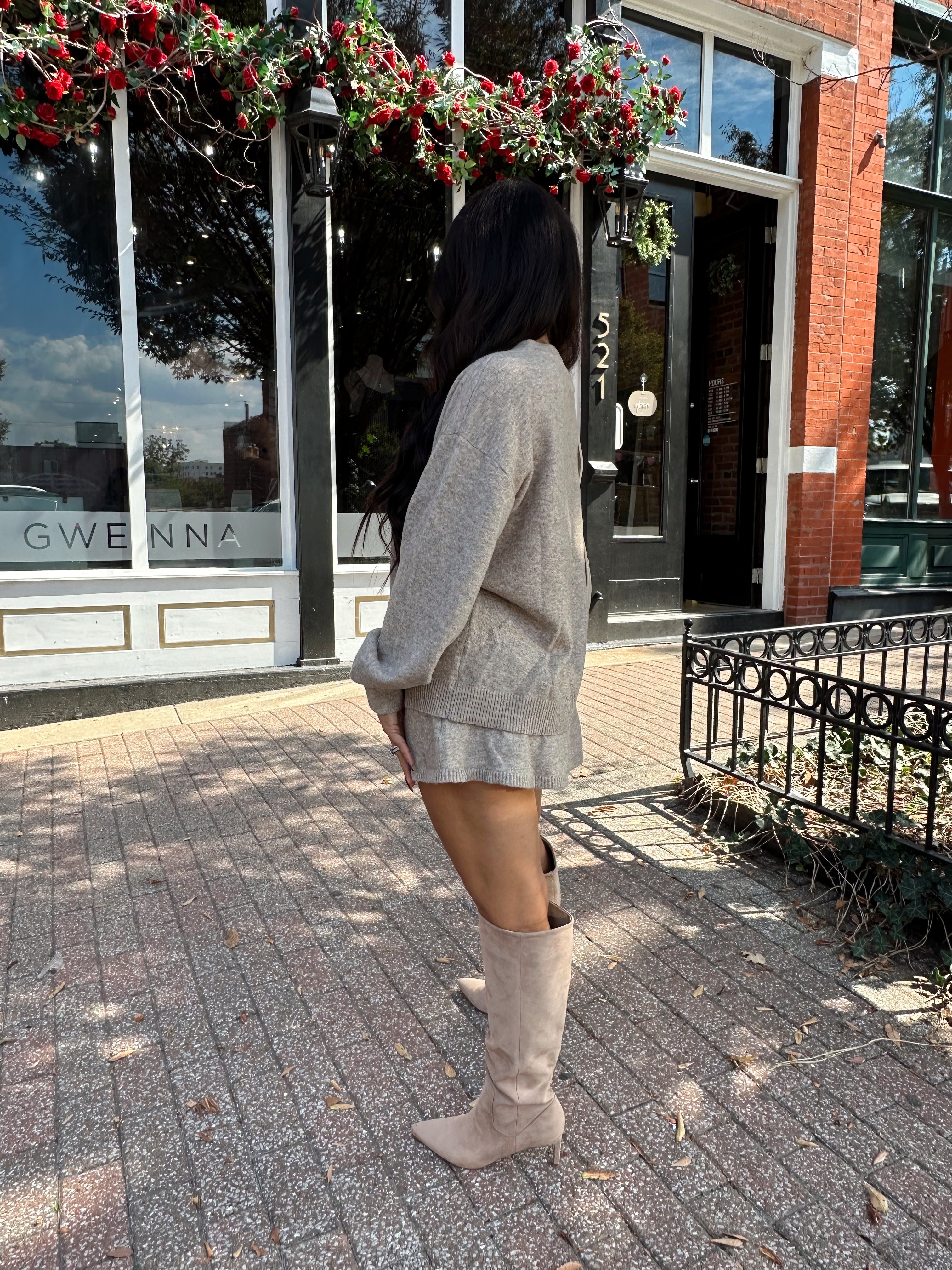 Woman wearing two piece sweater set with button down detailing, and built in shorts. 