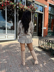 Woman wearing two piece sweater set with button down detailing, and built in shorts. 