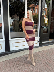 Woman wearing strapless maroon and beige striped knit midi dress with knee-high beige boots.