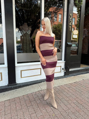 Woman wearing strapless maroon and beige striped knit midi dress with knee-high beige boots.
