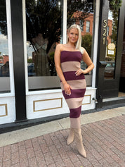 Woman wearing strapless maroon and beige striped knit midi dress with knee-high beige boots.