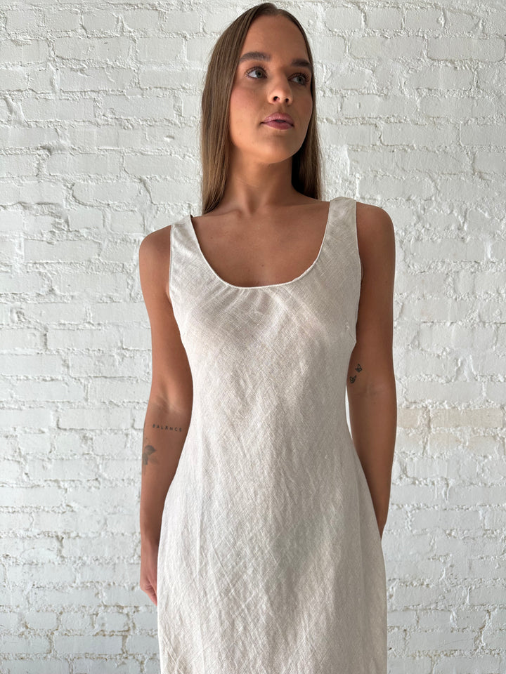 Woman wearing beige linen maxi dress with scoop neckline. 