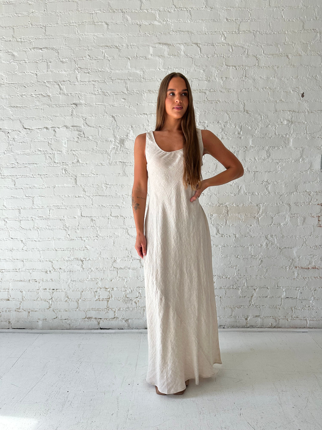 Woman wearing beige linen maxi dress with scoop neckline. 