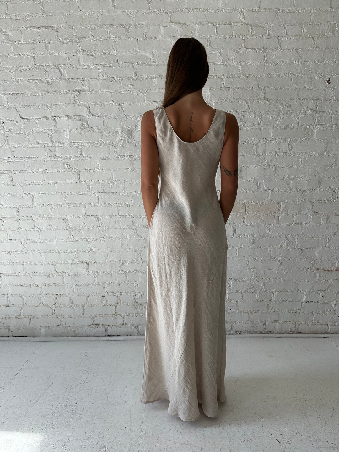 Woman wearing beige linen maxi dress with scoop neckline. 