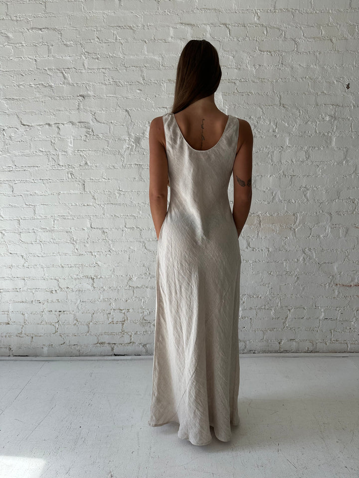 Woman wearing beige linen maxi dress with scoop neckline. 