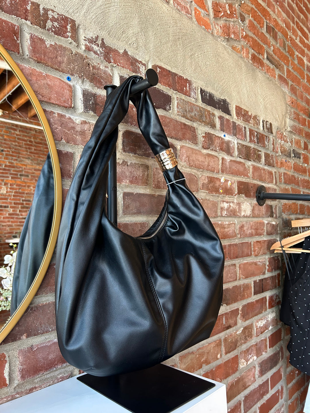 Black faux leather slouchy shoulder bag with gold hardware detail, and zipper closure. 