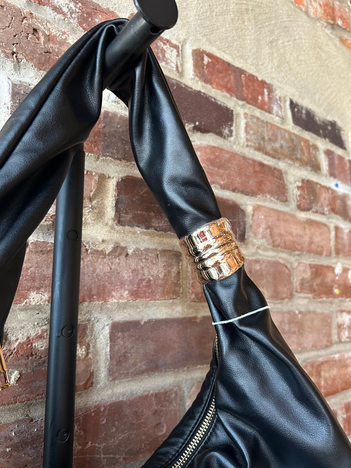 Black faux leather slouchy shoulder bag with gold hardware detail, and zipper closure. 