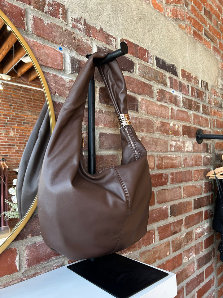 Dark brown faux leather slouchy shoulder bag with gold hardware detail, and zipper closure. 