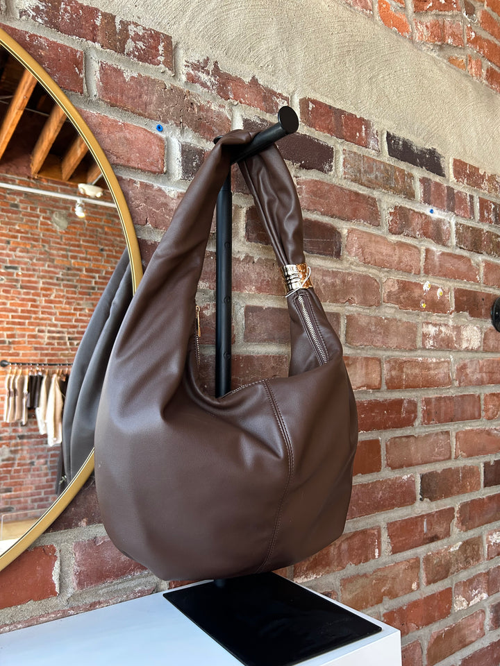 Dark brown faux leather slouchy shoulder bag with gold hardware detail, and zipper closure. 