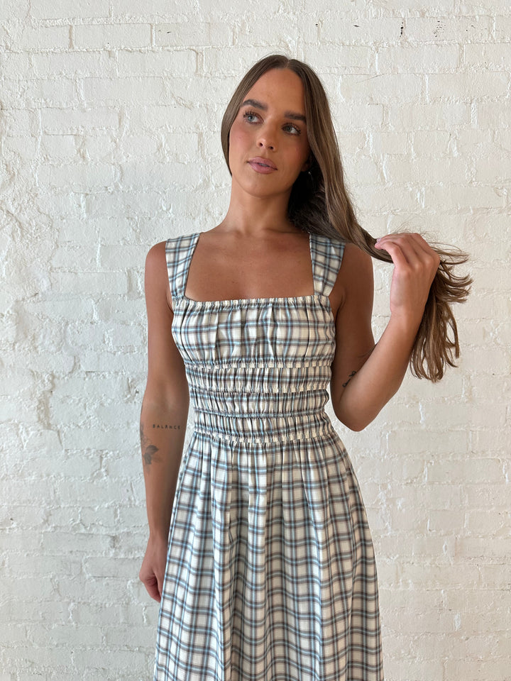 Woman wearing neutral plaid maxi dress with a smocked midsection, and elastic straight neckline 