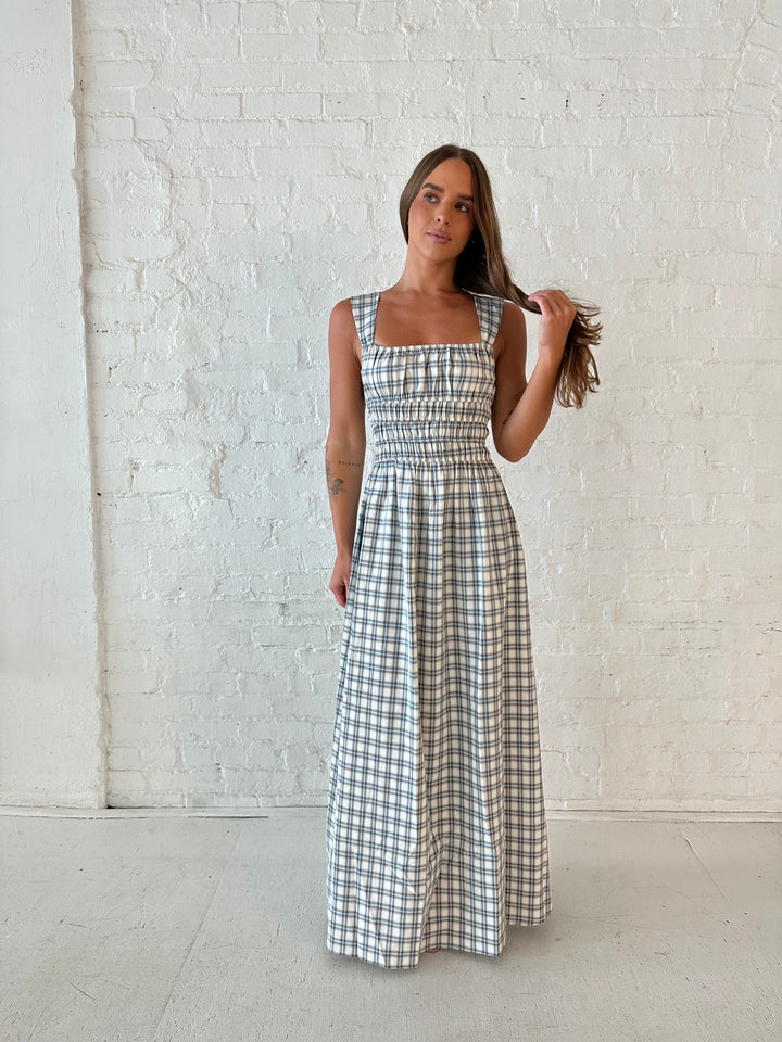 Woman wearing neutral plaid maxi dress with a smocked midsection, and elastic straight neckline 