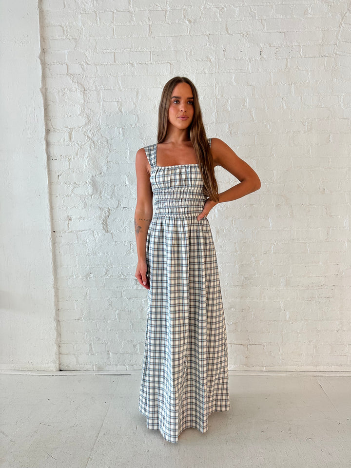 Woman wearing neutral plaid maxi dress with a smocked midsection, and elastic straight neckline 