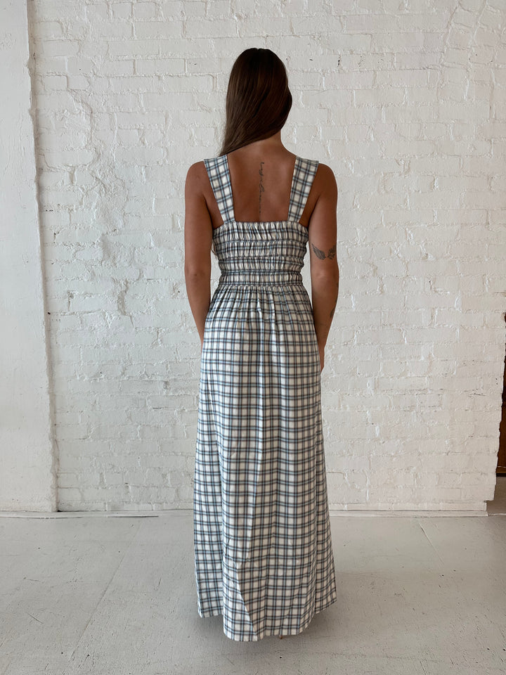 Woman wearing neutral plaid maxi dress with a smocked midsection, and elastic straight neckline 