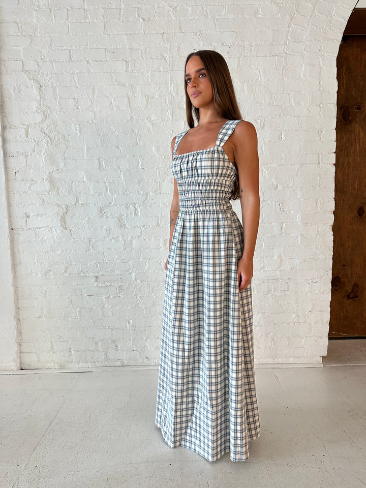 Woman wearing neutral plaid maxi dress with a smocked midsection, and elastic straight neckline 