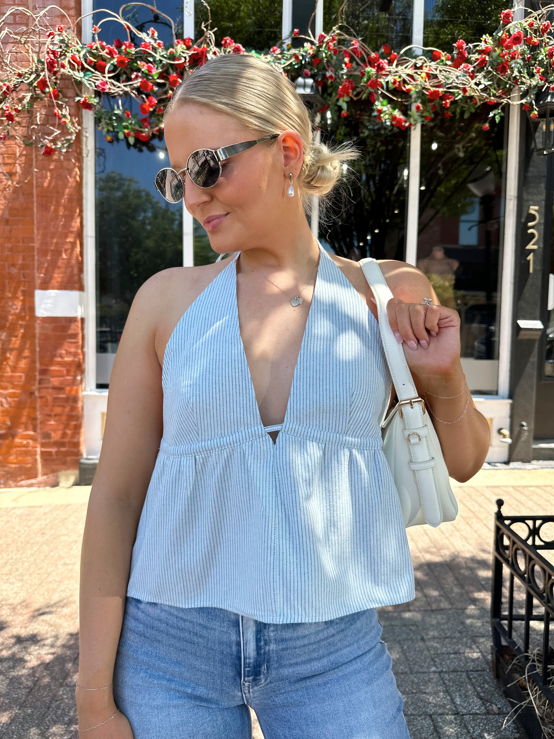 Woman wearing blue striped peplum top with self tie halter neck, and back closure. 