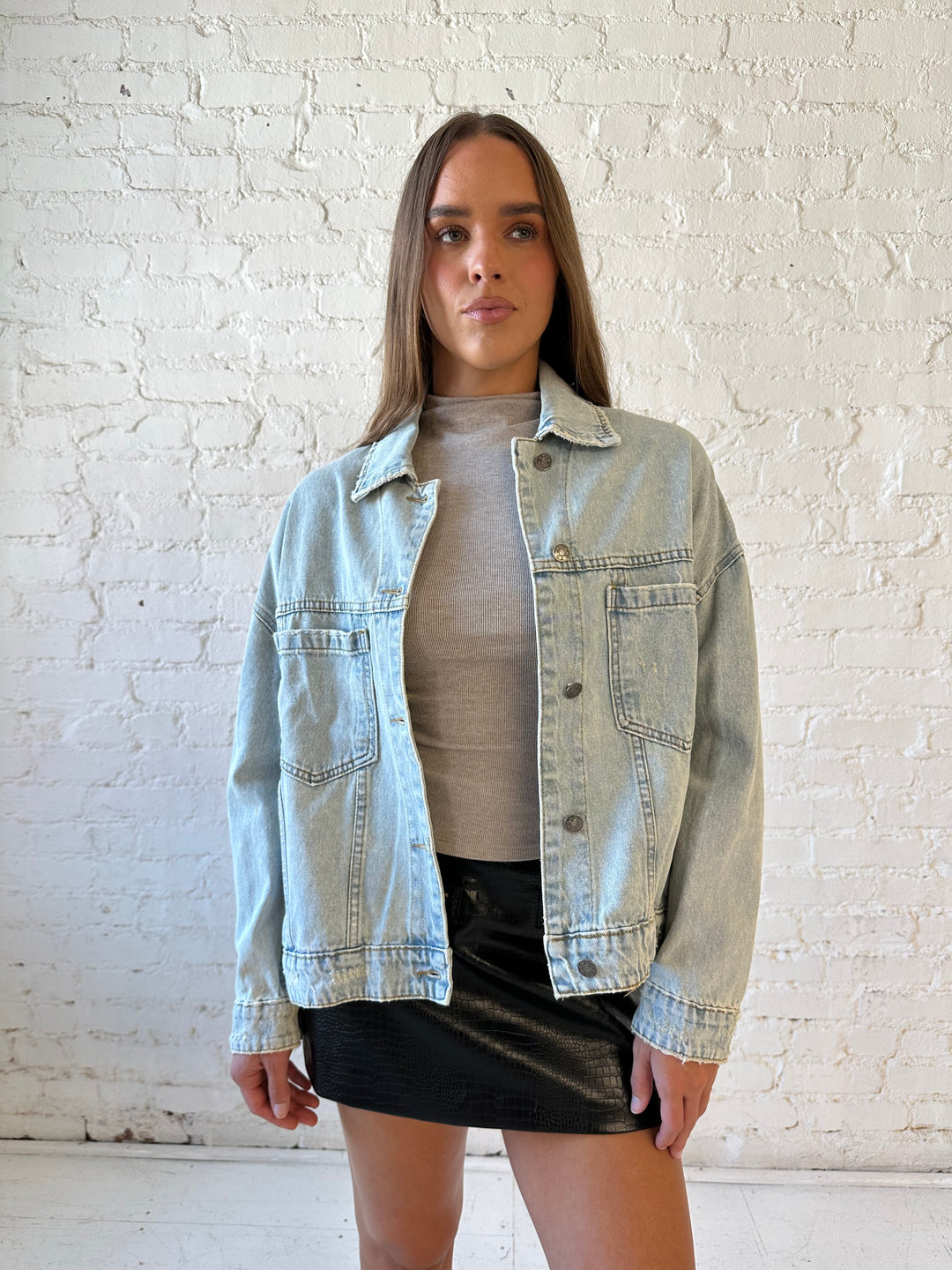 Woman wearing light wash relaxed fit denim jacket with high waisted mini skort and neutral top.