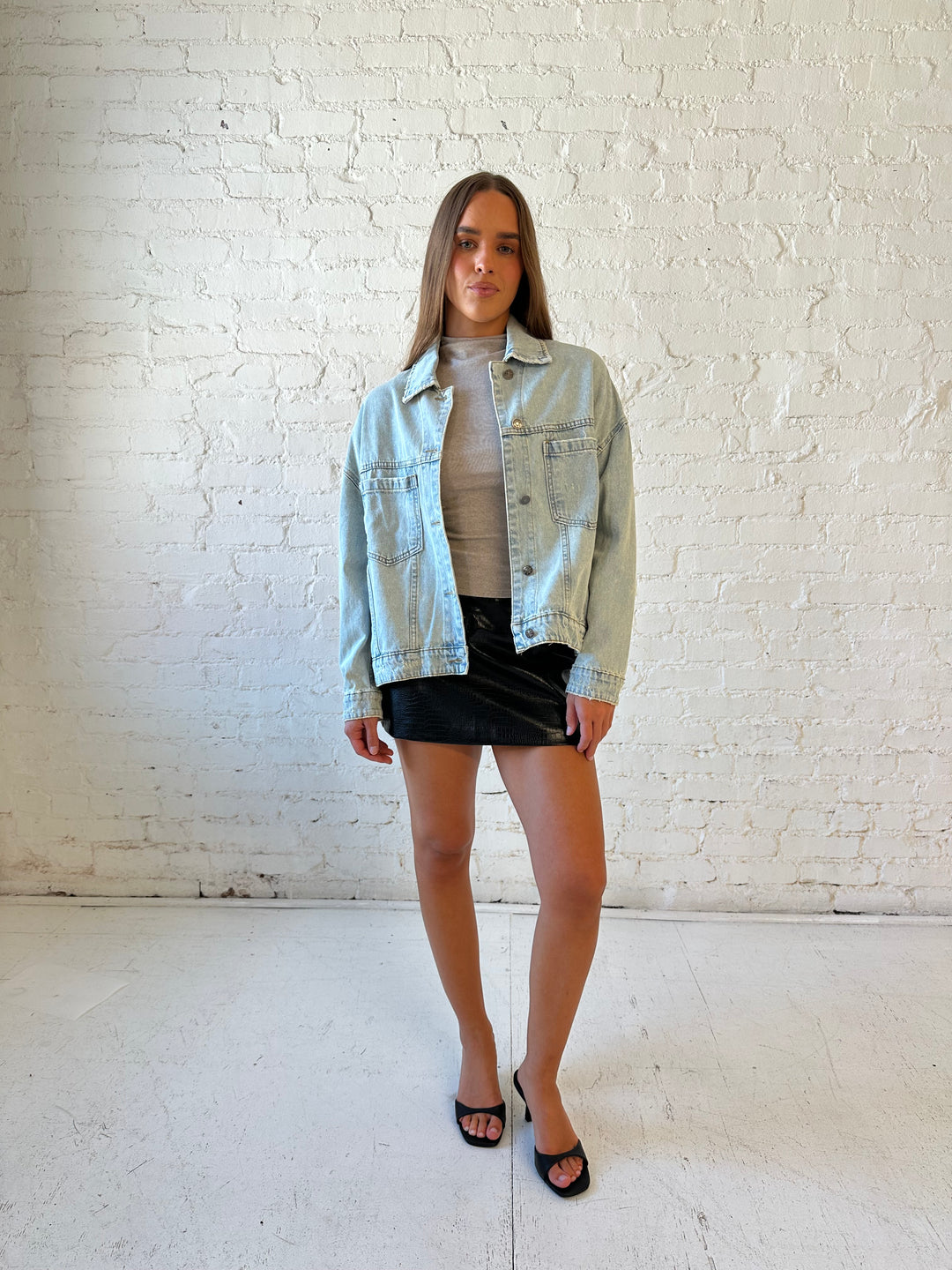 Woman wearing light wash relaxed fit denim jacket with high waisted mini skort and neutral top.