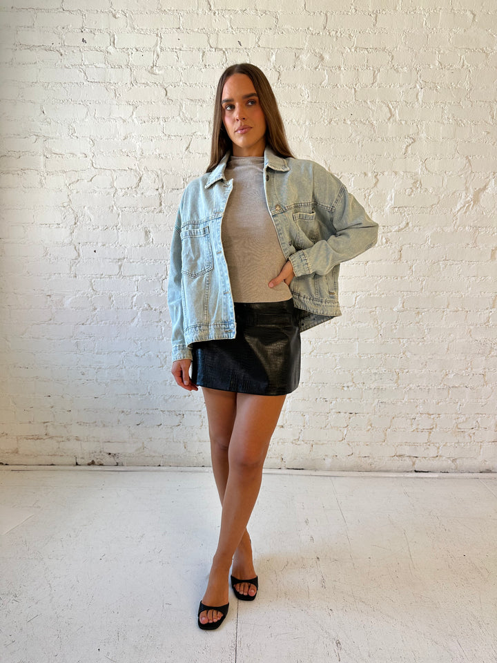 Woman wearing light wash relaxed fit denim jacket with high waisted mini skort and neutral top.