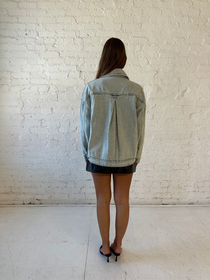Woman wearing light wash relaxed fit denim jacket with high waisted mini skort and neutral top.
