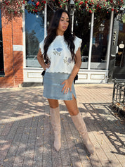 Woman wearing denim mini skirt with cable knit sweater top.