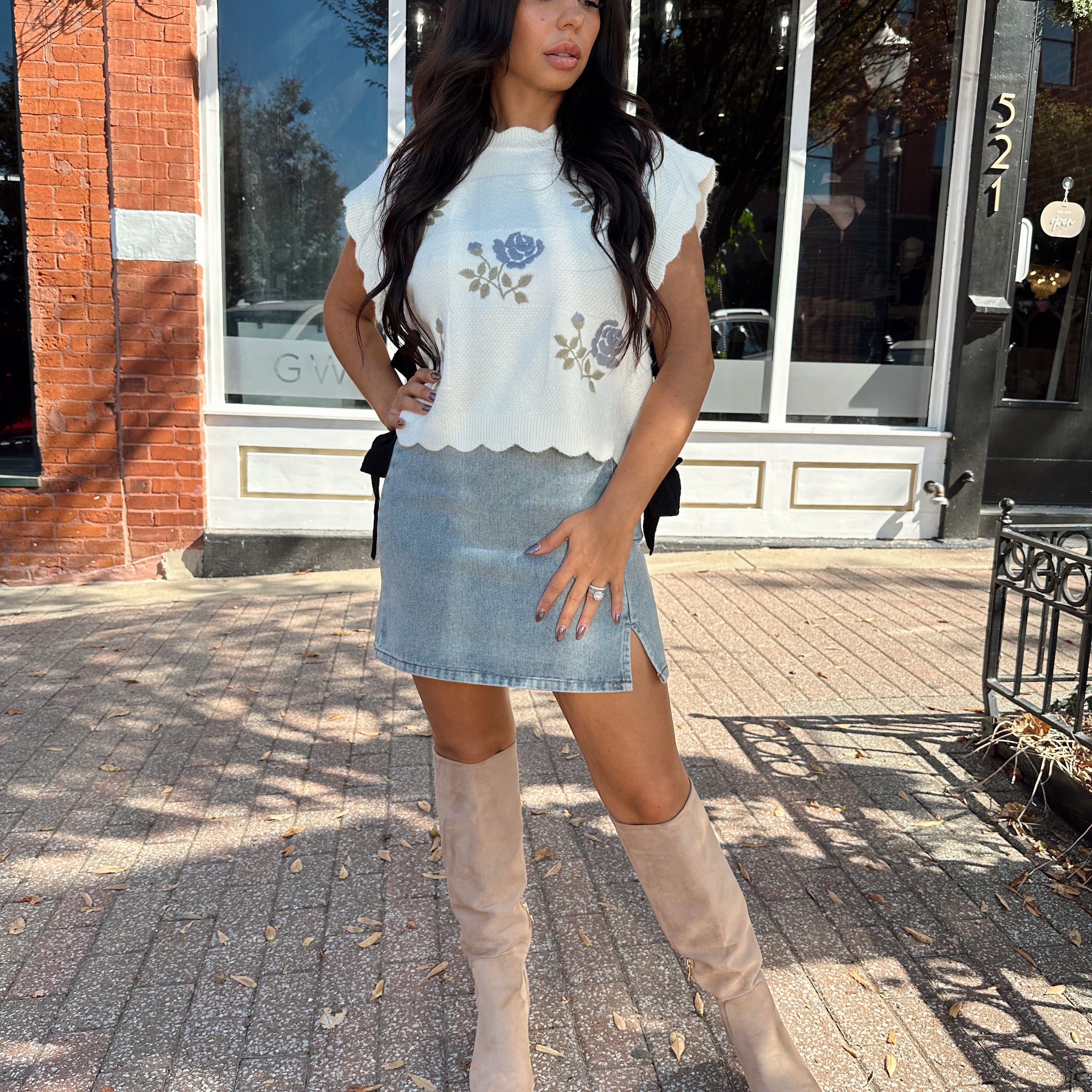 Woman wearing denim mini skirt with cable knit sweater top.