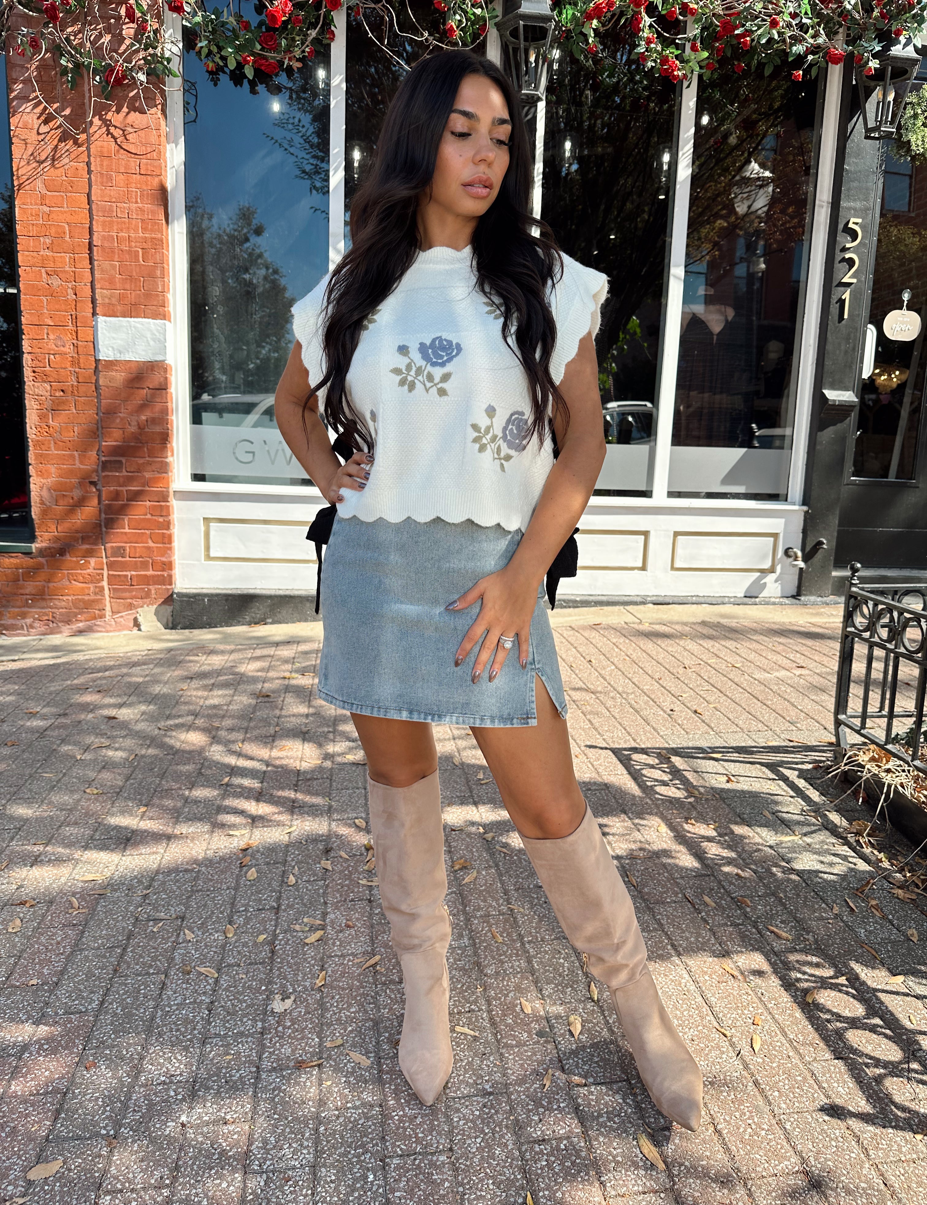 Woman wearing denim mini skirt with cable knit sweater top.
