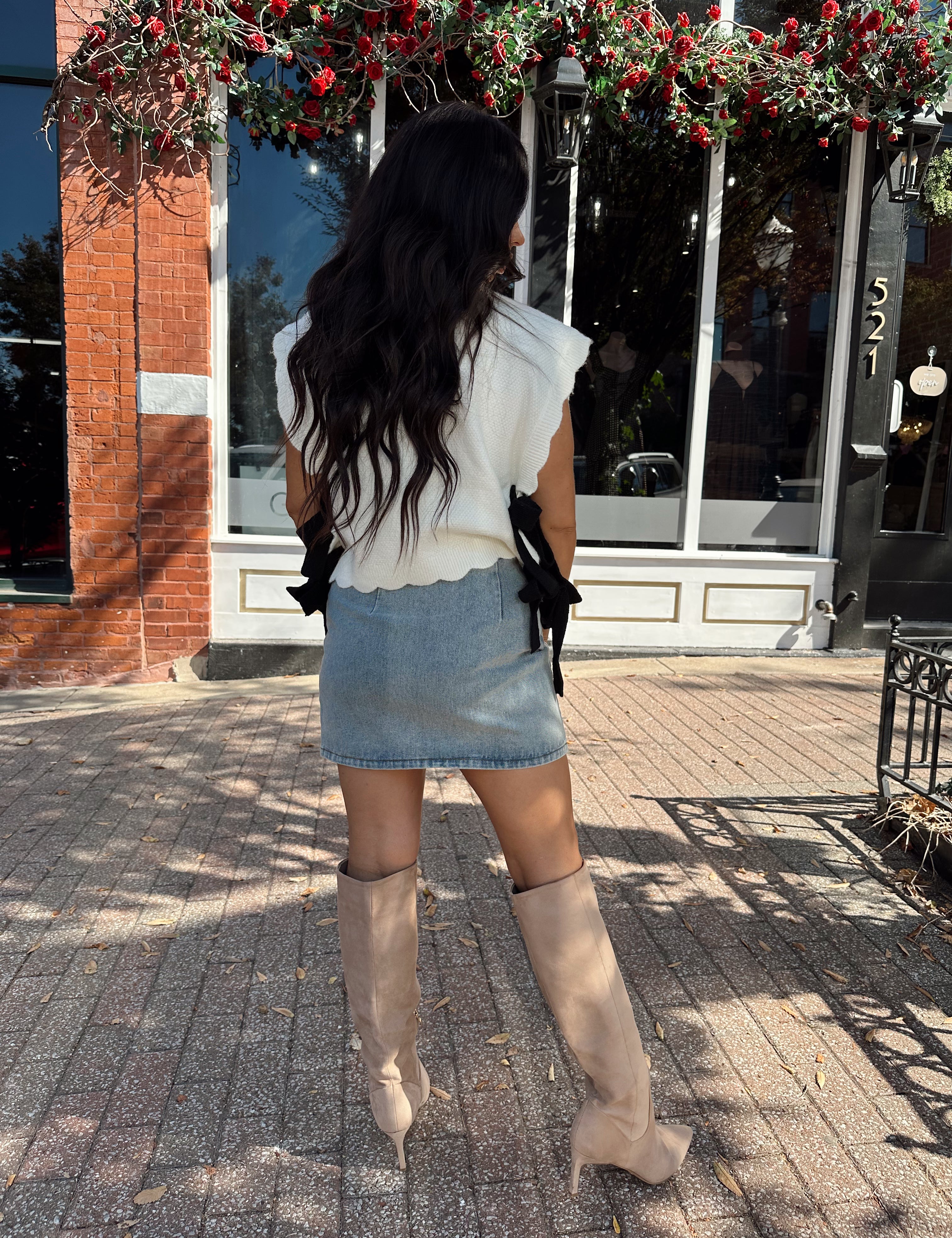 Woman wearing denim mini skirt with cable knit sweater top.