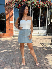 Woman wearing denim mini skirt with cable knit sweater top.