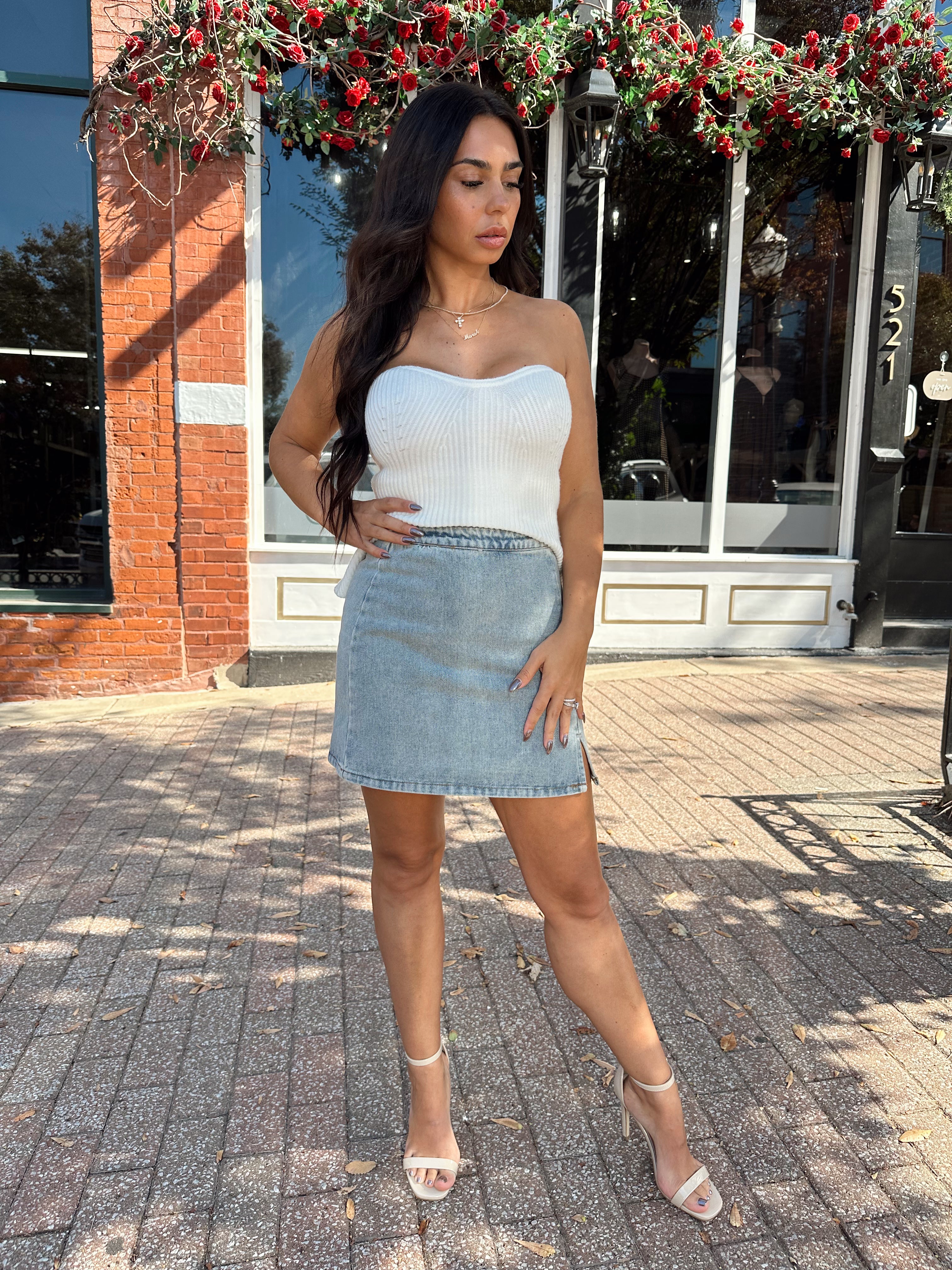Woman wearing denim mini skirt with cable knit sweater top.