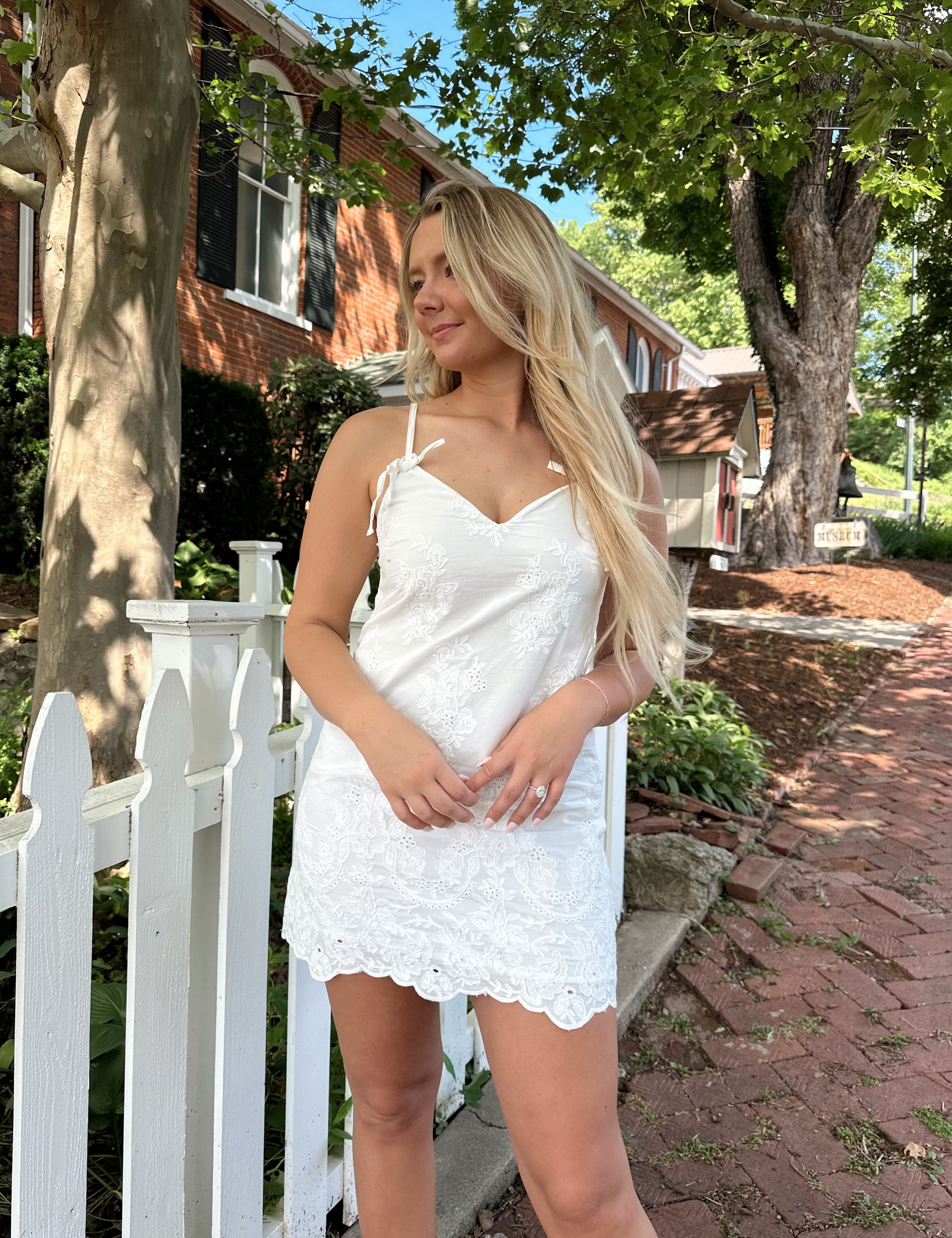 White lace mini dress with tie strap and scallop hem detailing.