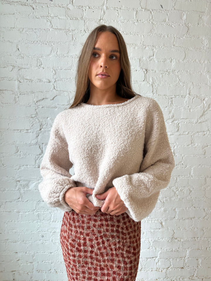Woman wearing beige knit sweater with burgundy textured dotted maxi skirt.