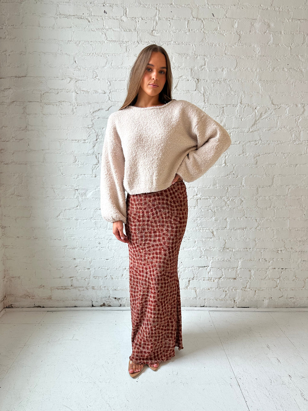 Woman wearing beige knit sweater with burgundy textured dotted maxi skirt.