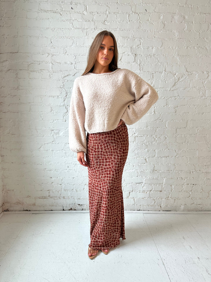 Woman wearing beige knit sweater with burgundy textured dotted maxi skirt.