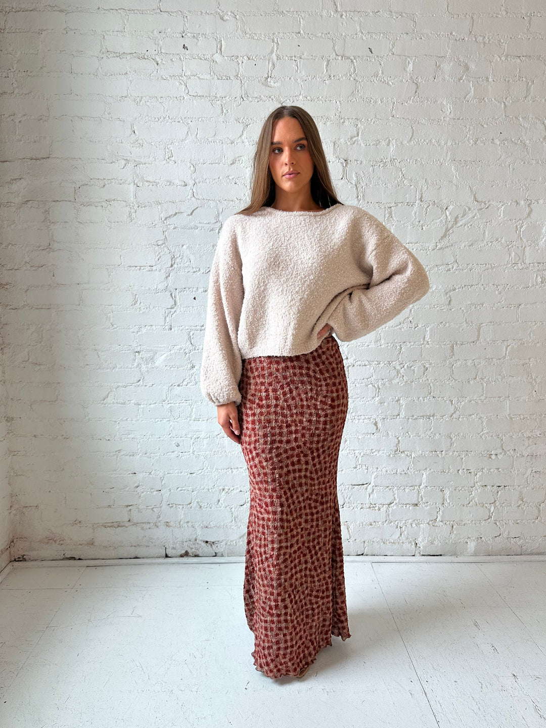 Woman wearing beige knit sweater with burgundy textured dotted maxi skirt.