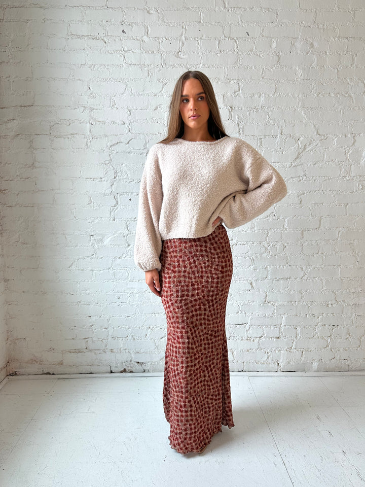 Woman wearing beige knit sweater with burgundy textured dotted maxi skirt.