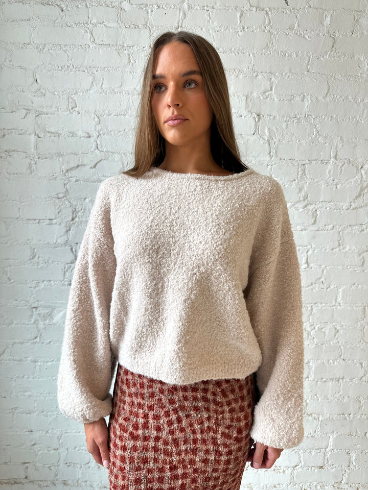 Woman wearing beige knit sweater with burgundy textured dotted maxi skirt.