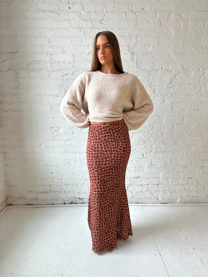 Woman wearing beige knit sweater with burgundy textured dotted maxi skirt.