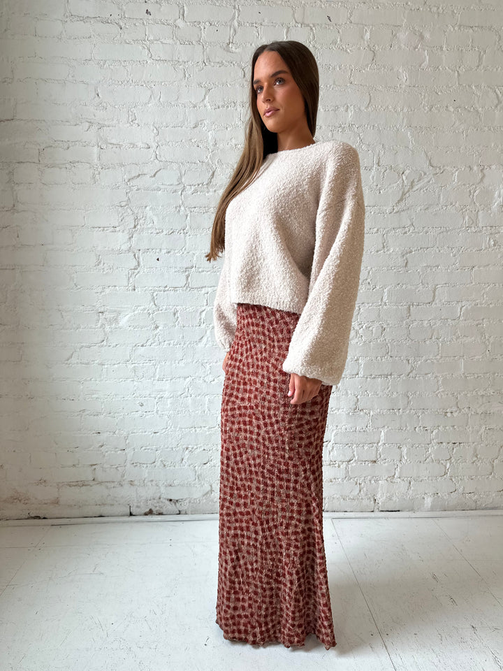 Woman wearing beige knit sweater with burgundy textured dotted maxi skirt.