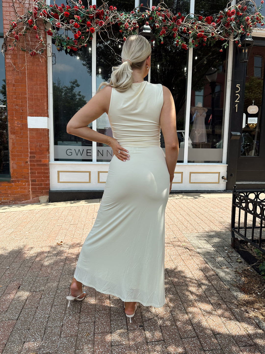 Woman wearing cream two piece set with maxi skirt with ring beaded detailing. 