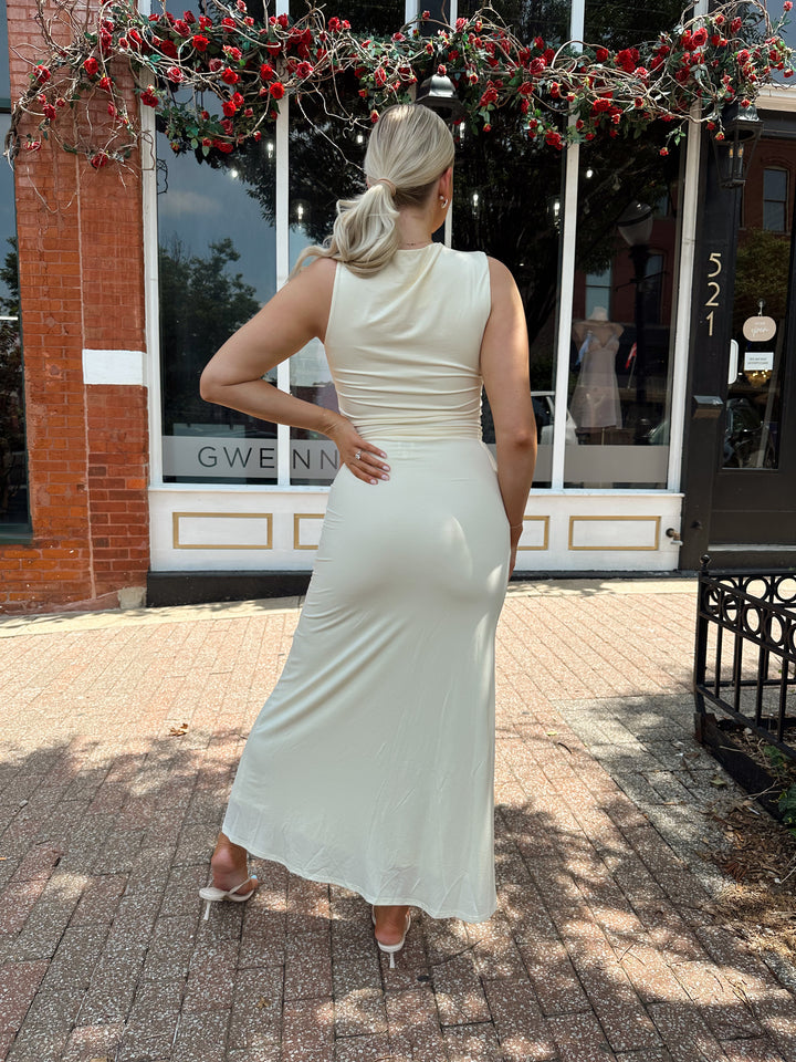 Woman wearing cream two piece set with maxi skirt with ring beaded detailing. 