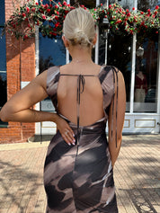 Woman wearing brown abstract pattern mesh midi dress with cowl neck and open back.