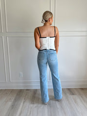 White eyelet corset with clasp closure and black trim.