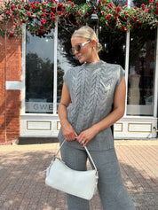 Woman wearing dark grey cable knit two piece sweater set with wide leg pant. 