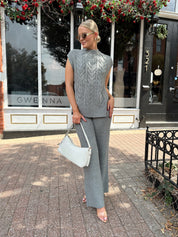 Woman wearing dark grey cable knit two piece sweater set with wide leg pant. 