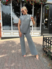 Woman wearing dark grey cable knit two piece sweater set with wide leg pant. 
