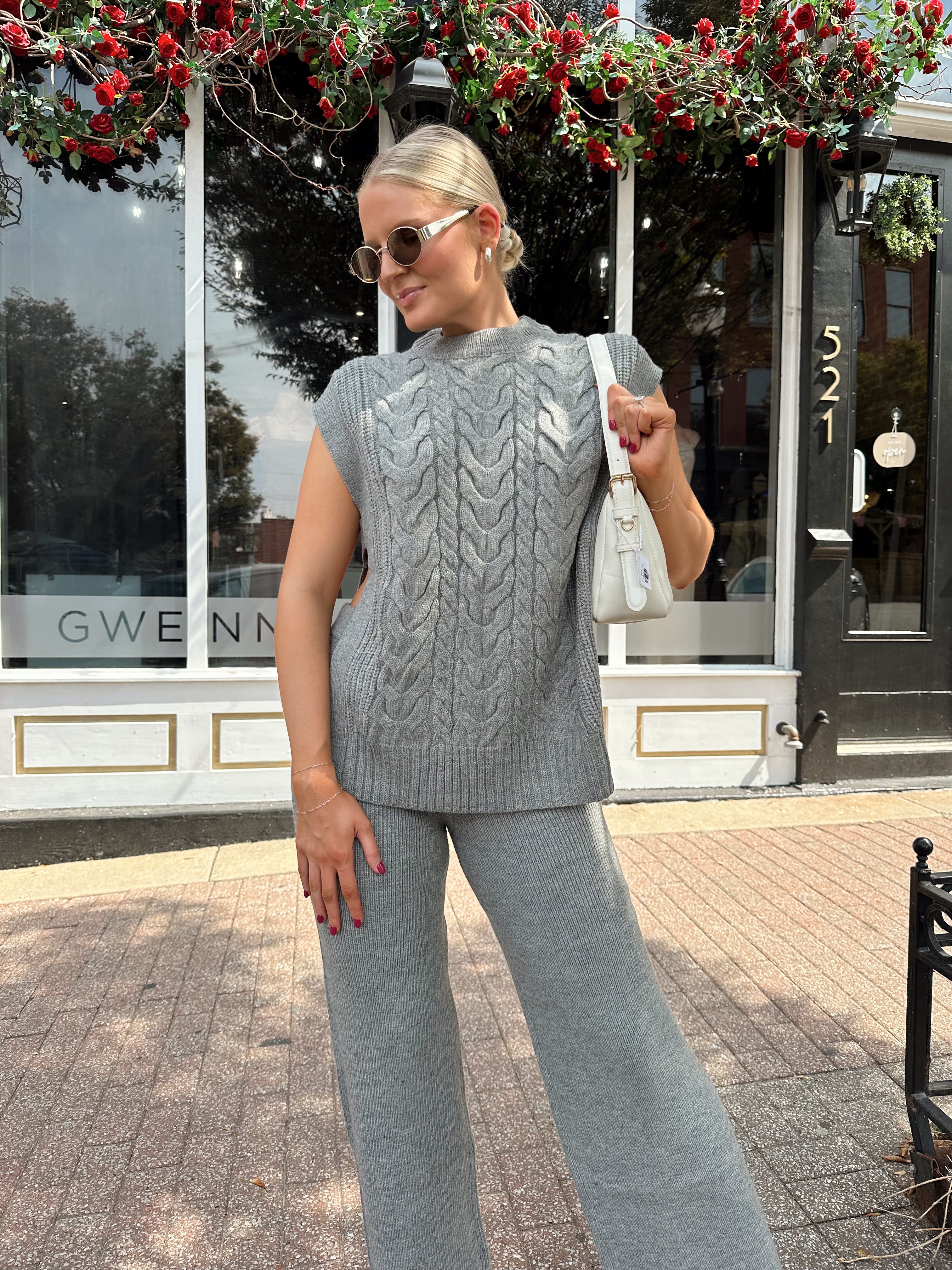 Woman wearing dark grey cable knit two piece sweater set with wide leg pant. 