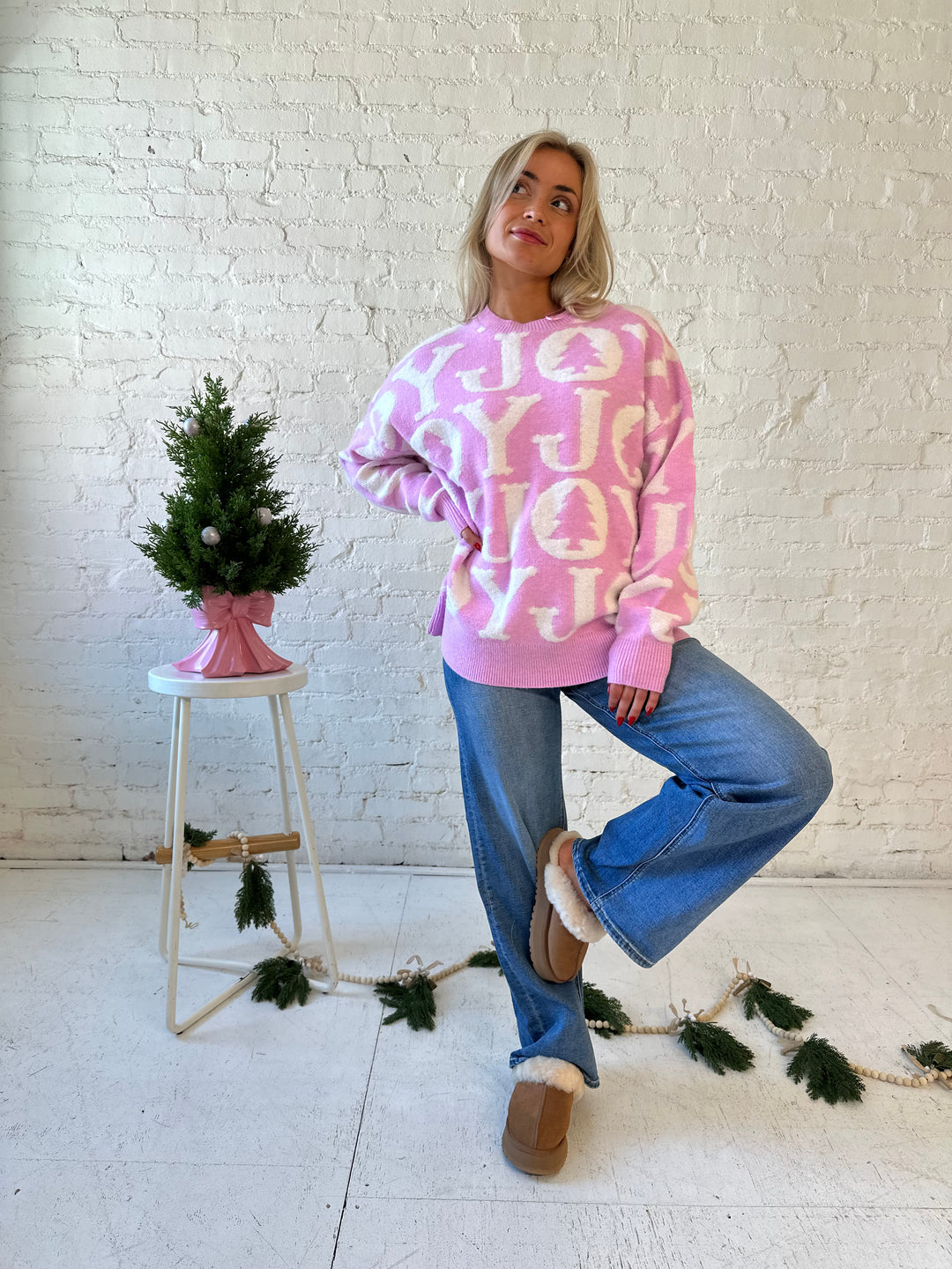 Woman wearing lilac purple oversized crewneck sweater with "Joy" written all over. 