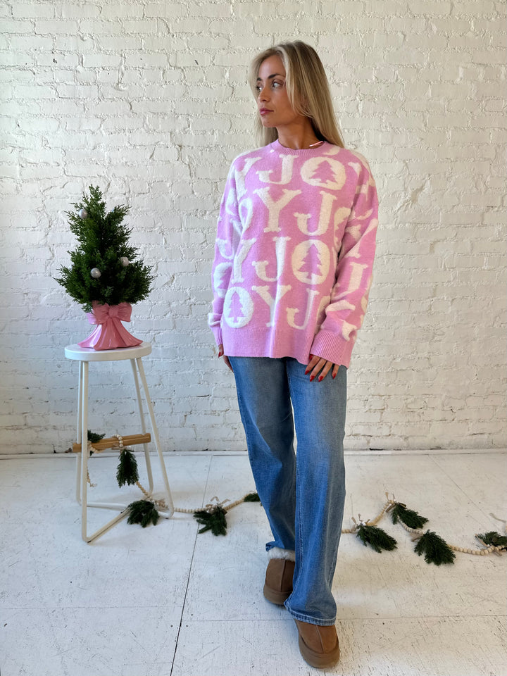 Woman wearing lilac purple oversized crewneck sweater with "Joy" written all over. 