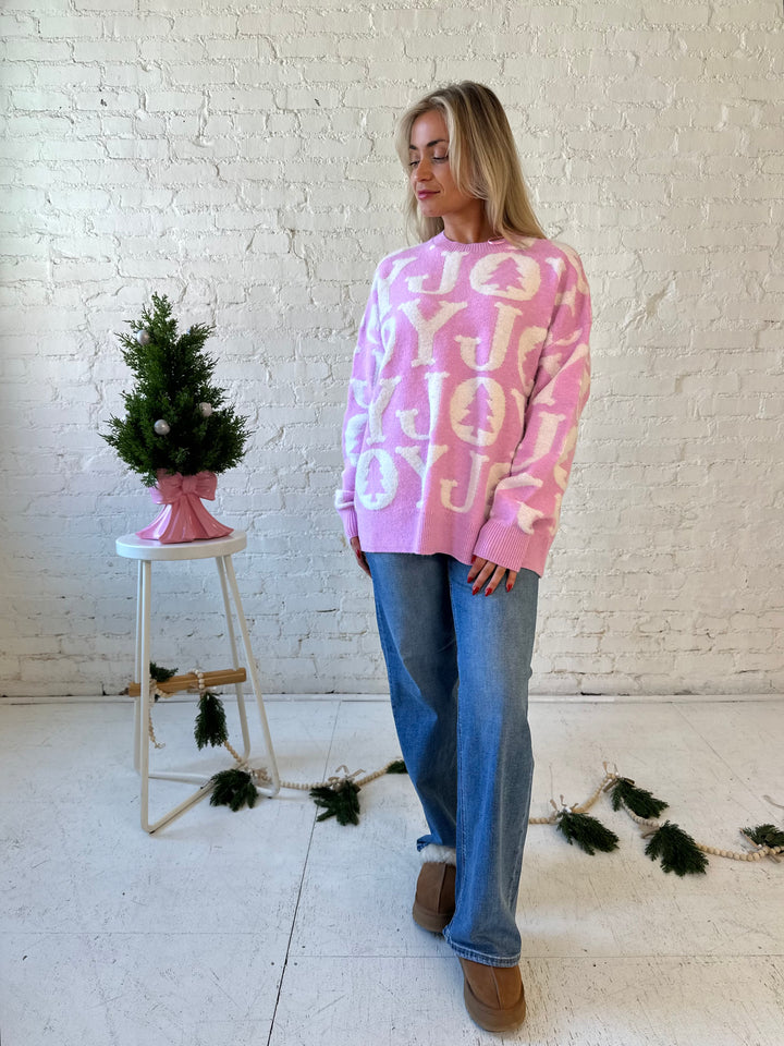 Woman wearing lilac purple oversized crewneck sweater with "Joy" written all over. 