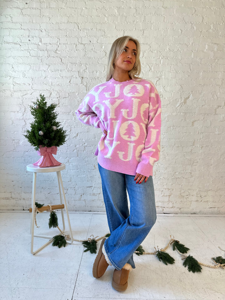Woman wearing lilac purple oversized crewneck sweater with "Joy" written all over. 